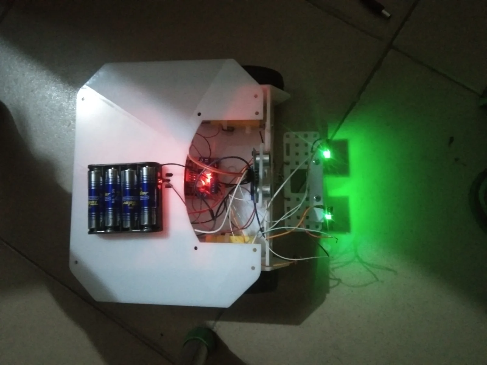 Student-built rover chassis running under green indicator LEDs
